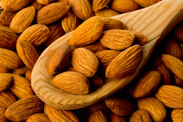 Heap of shelled almond kernels in wooden spoon