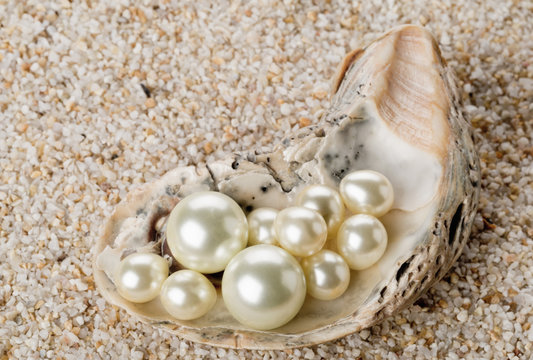 Multiple pearls in oyster sea shell on sand