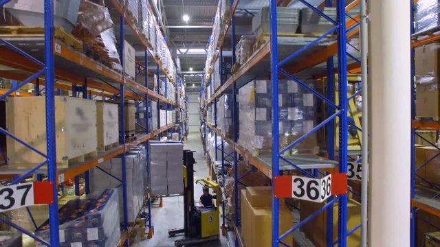 A reach truck loads new cargo on a warehouse racking shelf. 