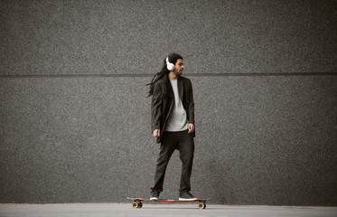 Close up of stylish handsome happy dreadlocks skater man in a suit standing on skate while...