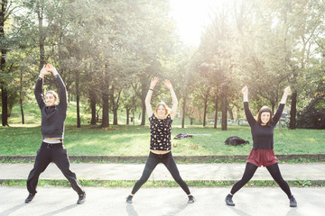 young woman and men doing jumping jacks oudoors back light - sport, training, active concept © Eugenio Marongiu
