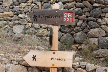 Wooden signpost showing directions to Banyalbufar and Planici on the GR 221 hiking trail
