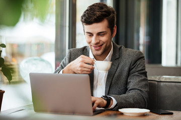 Pleased business man sitting by the table in cafe