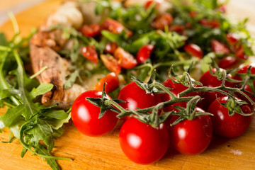 Pizza with cherry tomatoes on bed of rocket