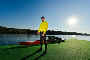 Naklejka premium Strong young man with his kayak on a sunny day on a lake. 