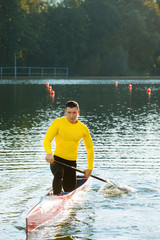 Strong young man with his kayak on a sunny day on a lake. 