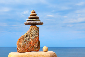 Stones balance on a background of blue sky and sea