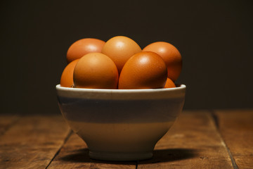 Easter bowl with Easter eggs on a wooden background.