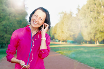 Mature woman listen music before or after jog in the park