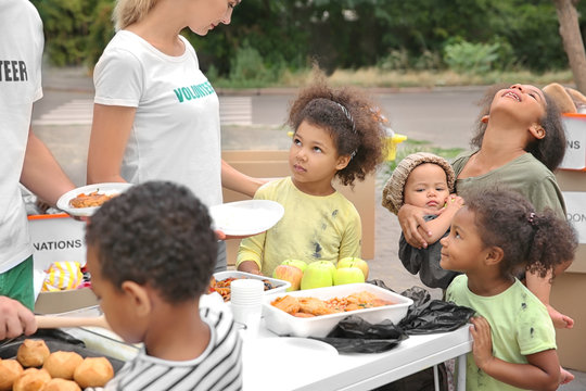 Volunteers sharing food with poor African children outdoors