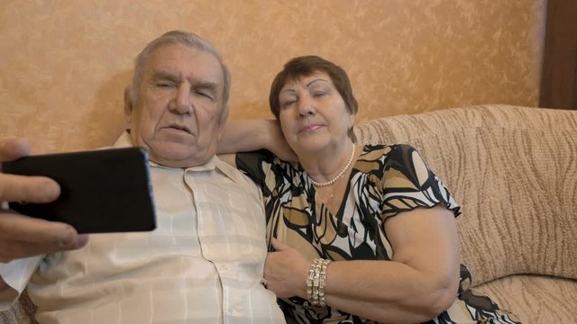 An adult couple makes selfie. Use a smartphone for photos