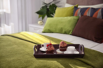 Tray with tasty breakfast on comfortable bed