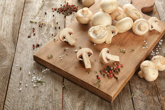 Fresh champignon mushrooms on wooden board