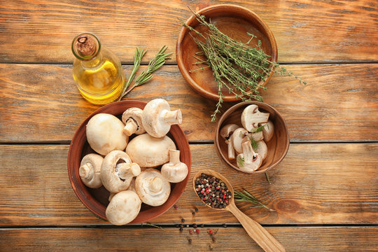 Bowls with fresh champignon mushrooms on wooden table