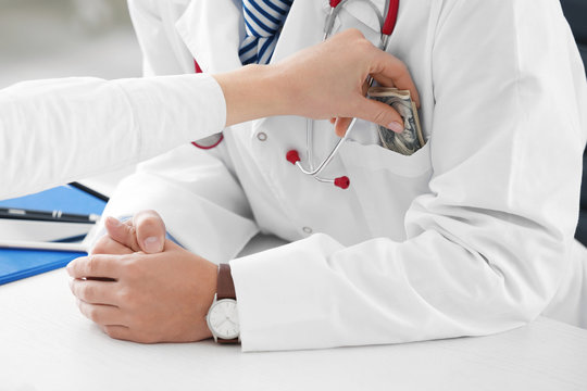 Woman putting money in pocket of doctor's coat indoors, closeup