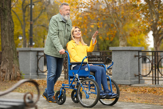 Senior man with his daughter in wheelchair outdoors on autumn day