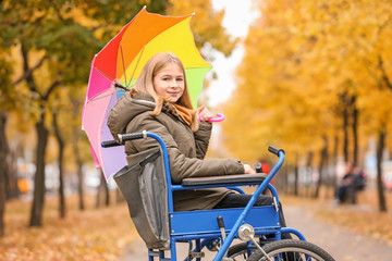 Teenage girl in wheelchair outdoors on autumn day