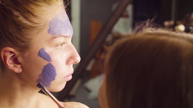Close up. Face art. The make-up artist begining to paint on the face of the model. Application of foundation