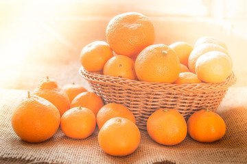 Fresh ripe fruit tangerine oranges in a basket with rustic background and with morning sunlight effect.