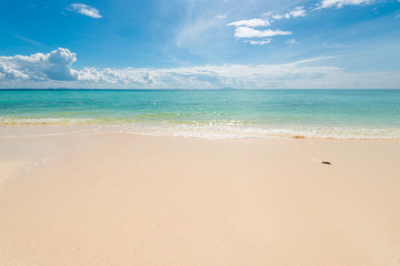 Fototapeta na wymiar fine sand on the beach, calm azure sea and beautiful clouds on a sunny day idealistic landscape