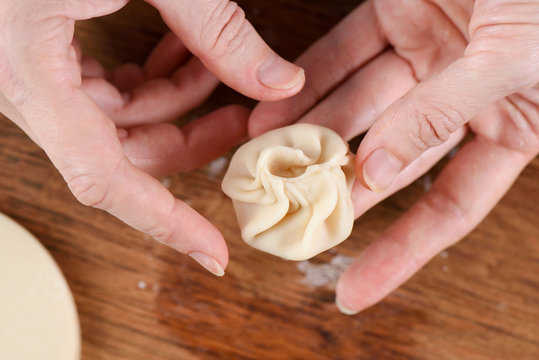 Cooking techniques. Closeup of woman hands making purse shape dumpling momo