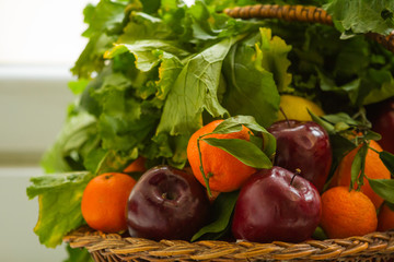 Cesto di mele e mandarini con cime di rapa