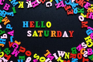 concept design - the word HELLO SATURDAY from multi-colored wooden letters on a black background, creative idea