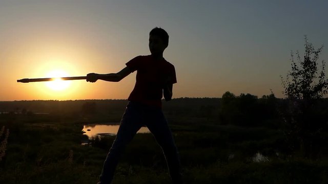Small Boy Strikes Kung-Fu Blows on a Lake Bank at Sunset in Autumn in Slo-Mo