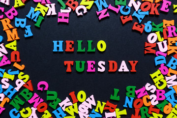 concept design - the word HELLO TUESDAY from multi-colored wooden letters on a black background, creative idea
