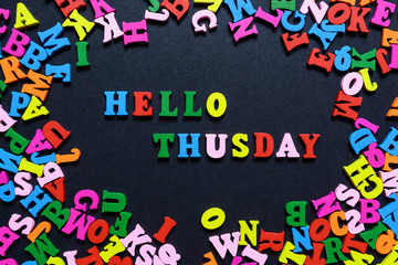 concept design - the word HELLO THUSDAY from multi-colored wooden letters on a black background, creative idea