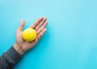 Mele hand holding yellow ball on blue background