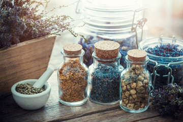 Bottles and jars of healing herbs, mortar and wooden box of dry flowers, herbal medicine.