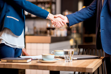Close-up view on the handshake between business couple at the cafe or restaurant
