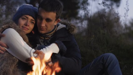 Romantic couple resting at bonfire in calm. Slowly