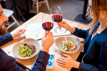 Business couple having a conversation during the dinner clinking glasses at the restaurant