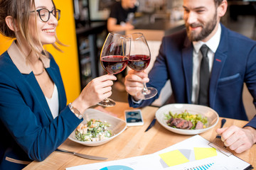 Business couple having a conversation during the dinner clinking glasses at the restaurant