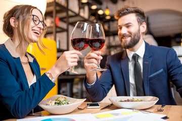 Business couple having a conversation during the dinner clinking glasses at the restaurant