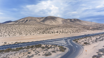 Fototapeta na wymiar Aerial view of desert road joining highway in arid, barren mountains area of Fuerteventura, Canary Islands, Spain .