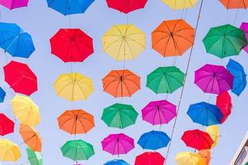 A field of open multi colored umbrellas used as sun protection at a public place somewhere at Torremolinos, Spain (different views) - obrazy, fototapety, plakaty