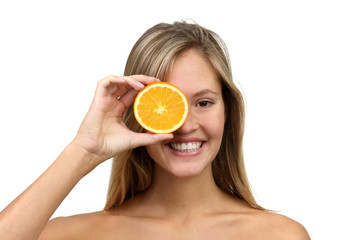 Hübsche blonde Frau mit nackten Schultern lacht und hält halbe Orange vor das Auge