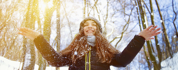 Young beautiful woman cheerfully rejoicing at snow in sunbeams. Fine winter day. (Christmas, new year, celebration concept)