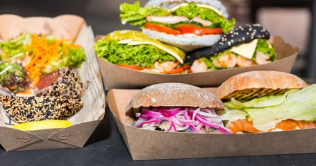 Tasty appetizing burgers with meat or fish, cheese and vegetables at outdoor food festival