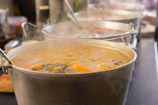 Spicy soup in large cauldrons with ladle inside at outdoor food festival