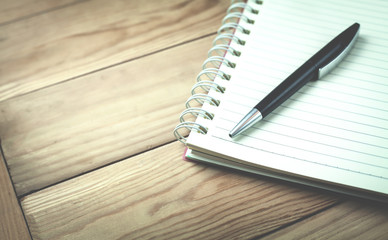 Notepad and pen on a wooden background.