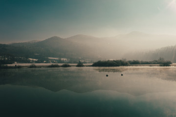 Mysterious lake on an early winter morning photographed in backlight in central Slovenia