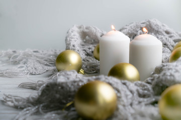 Obraz na płótnie Canvas White holiday candles by silver toy, Happy New Year and knitted plaid rustic wooden background; holiday background with white copy space