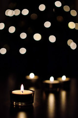 Four burning advent tea candles on wood table with bokeh background. Symbol of Christmas time.
