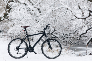 Winter season cycling. Black bicycle on the snow. Sport at any time of year concept.