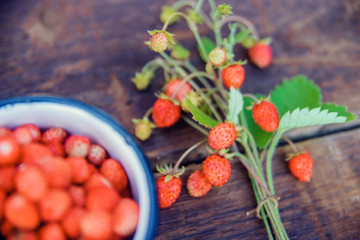 Wild strawberries in a white mug on the rustic board, organic food