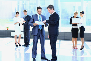 Fototapeta premium employees discuss working papers, standing in the lobby